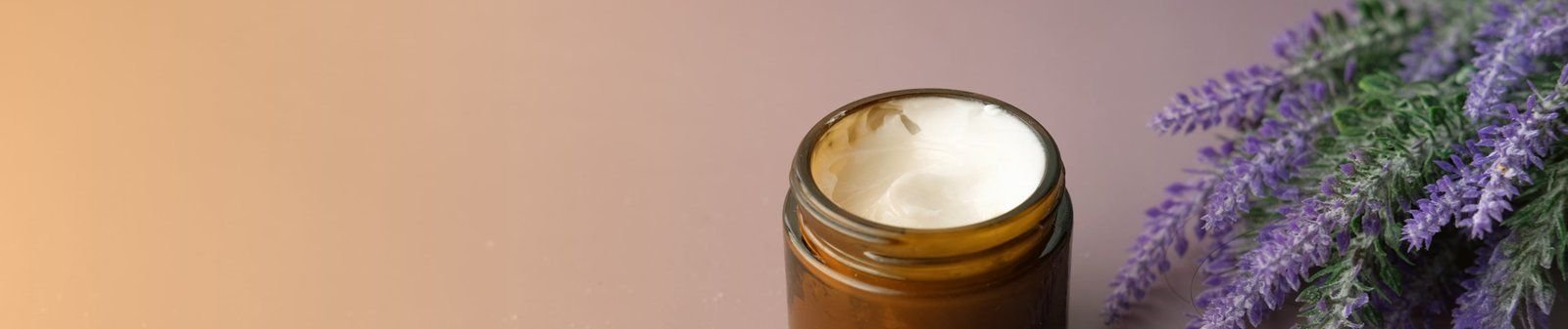 Frasco de crema Juveness junto a ramas de lavanda